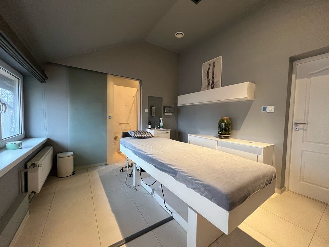 pokój - gabinet masażu z łóżkiem do masażu pośrodku pomieszczenia