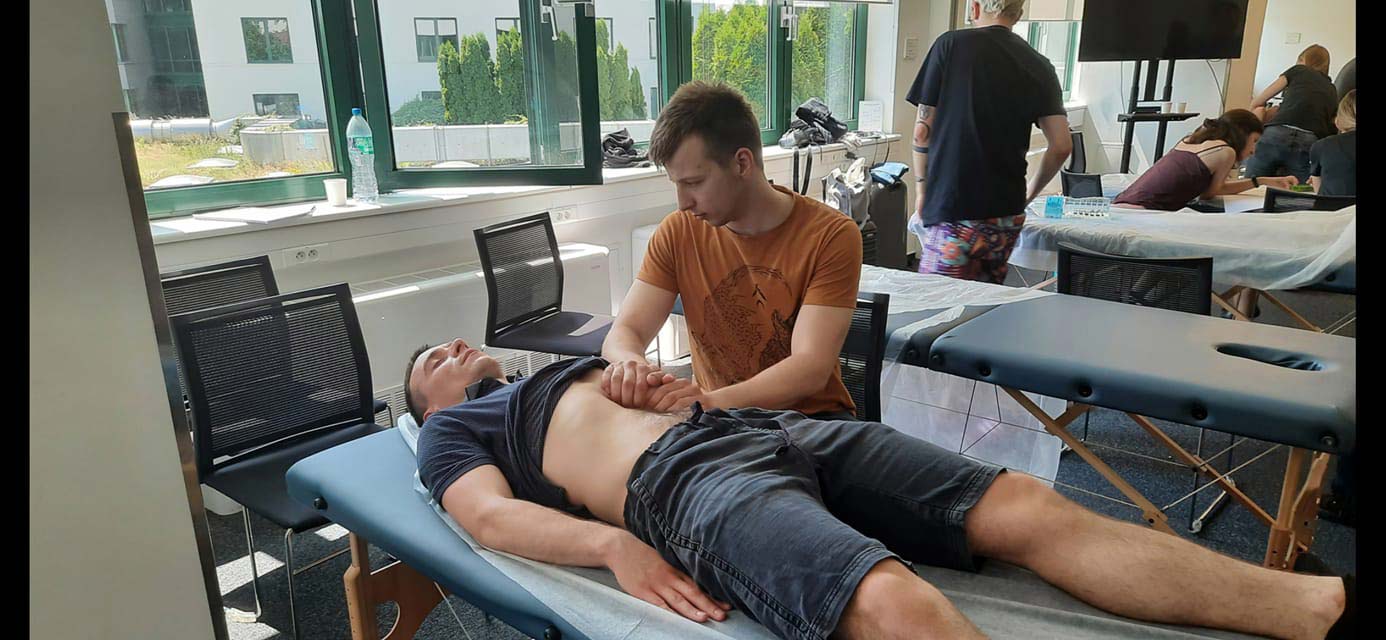 fizjoterapeuta uczy się masażu pacjenta leżącego na łóźku